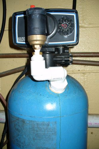 Close-up of a water softener control valve head on a blue mineral tank