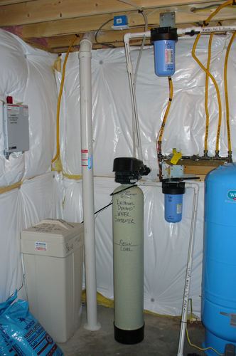 EcoSoft electronic demand water softener with brine tank and whole-house carbon filter in an unfinished basement