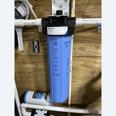 Pentair Big Blue whole-house sediment filter housing mounted on a wall