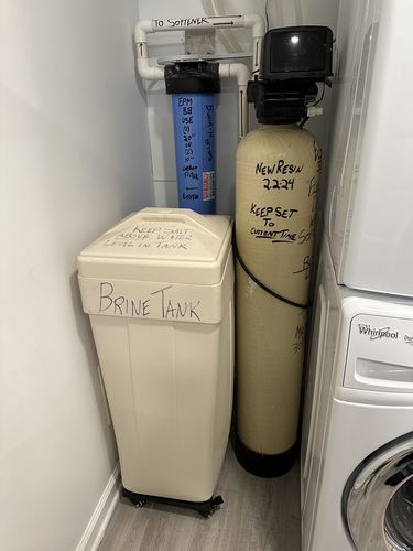 Water softener and brine tank installed in a tight laundry closet next to a washer and dryer