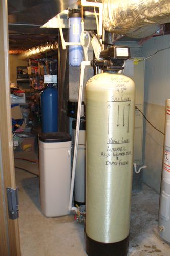EcoSoft acid neutralizer and RainSoft filtration equipment installed along a basement wall