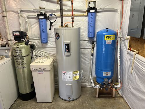 EcoSoft 64K water softener with dual whole-house carbon filters, a water heater, and a ProFlo well pressure tank