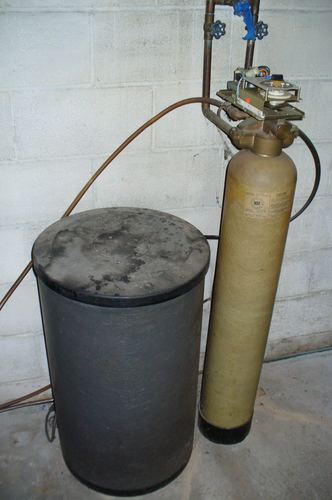 Older water softener and filter tank system installed in a basement