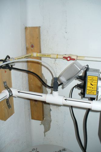 Close-up of plumbing fittings and a flow switch control box