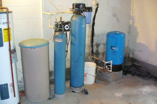 Older water softener and iron filter tanks with a pressure tank