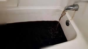 Black manganese-stained water running from a bathtub faucet