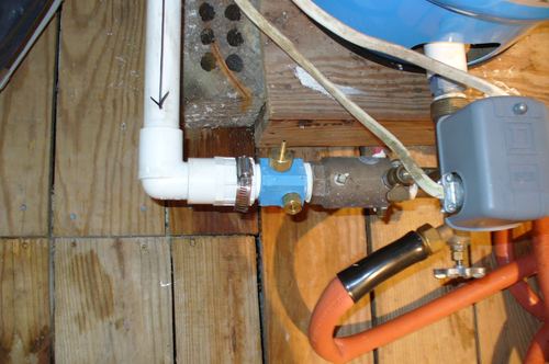 Close-up of plumbing fittings and a pressure switch for a well pump system