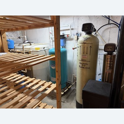 Full water treatment system installed in a crawlspace, including pressure tank, acid neutralizer, and water softener