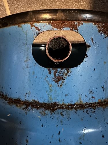 Close-up of rust and mineral buildup on a pressure tank drain fitting