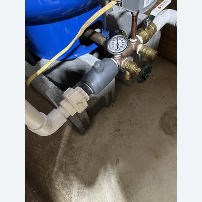 Close-up of a pressure gauge and shutoff valves on a well pump system