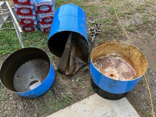 Old rusted metal drums cut open outdoors, ready for disposal