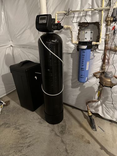 Water softener with a whole-house carbon filter, brine tank, and copper plumbing