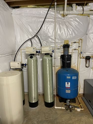 Older water softener and pressure tank system installed in a basement