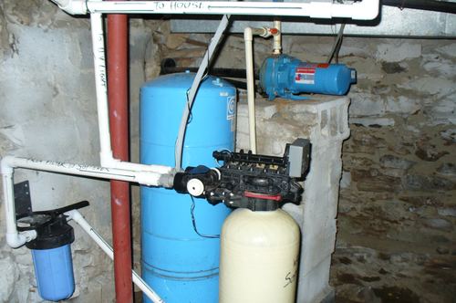 Goulds well pump, pressure tank, and UV light plumbing routed to the house