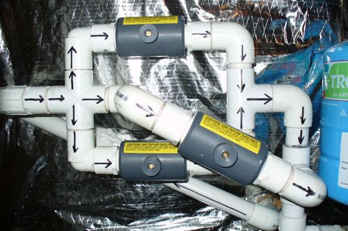 Close-up of a PVC plumbing manifold with backwash valves