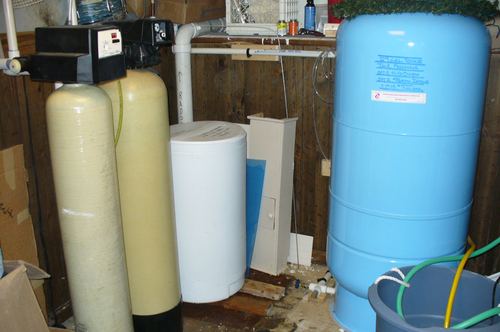 Two water treatment tanks and a well pressure tank installed in a basement