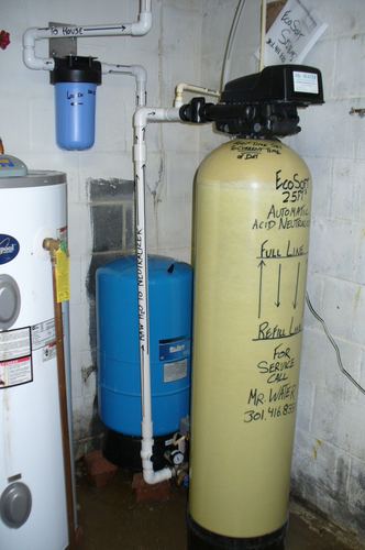 Close-up of an EcoSoft acid neutralizer with a well pressure tank and water heater