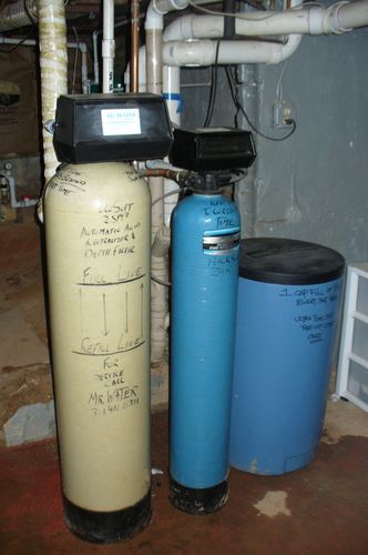 Close-up of an EcoSoft acid neutralizer and iron filter with handwritten service notes