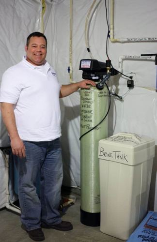 Scott Handy standing next to his patented EcoVent 32K water softener and brine tank