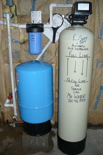 EcoSoft acid neutralizer with a pressure tank and whole-house filters in a stone-wall basement