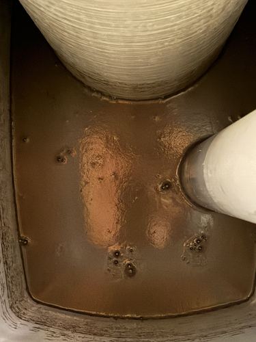 Close-up of the corroded, rust-stained interior of an old brine tank