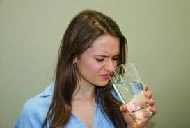 Woman reacting to sulfur smell from tap water